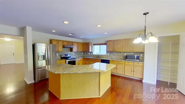 a view of a kitchen with kitchen island a counter top space appliances and a ceiling fan
