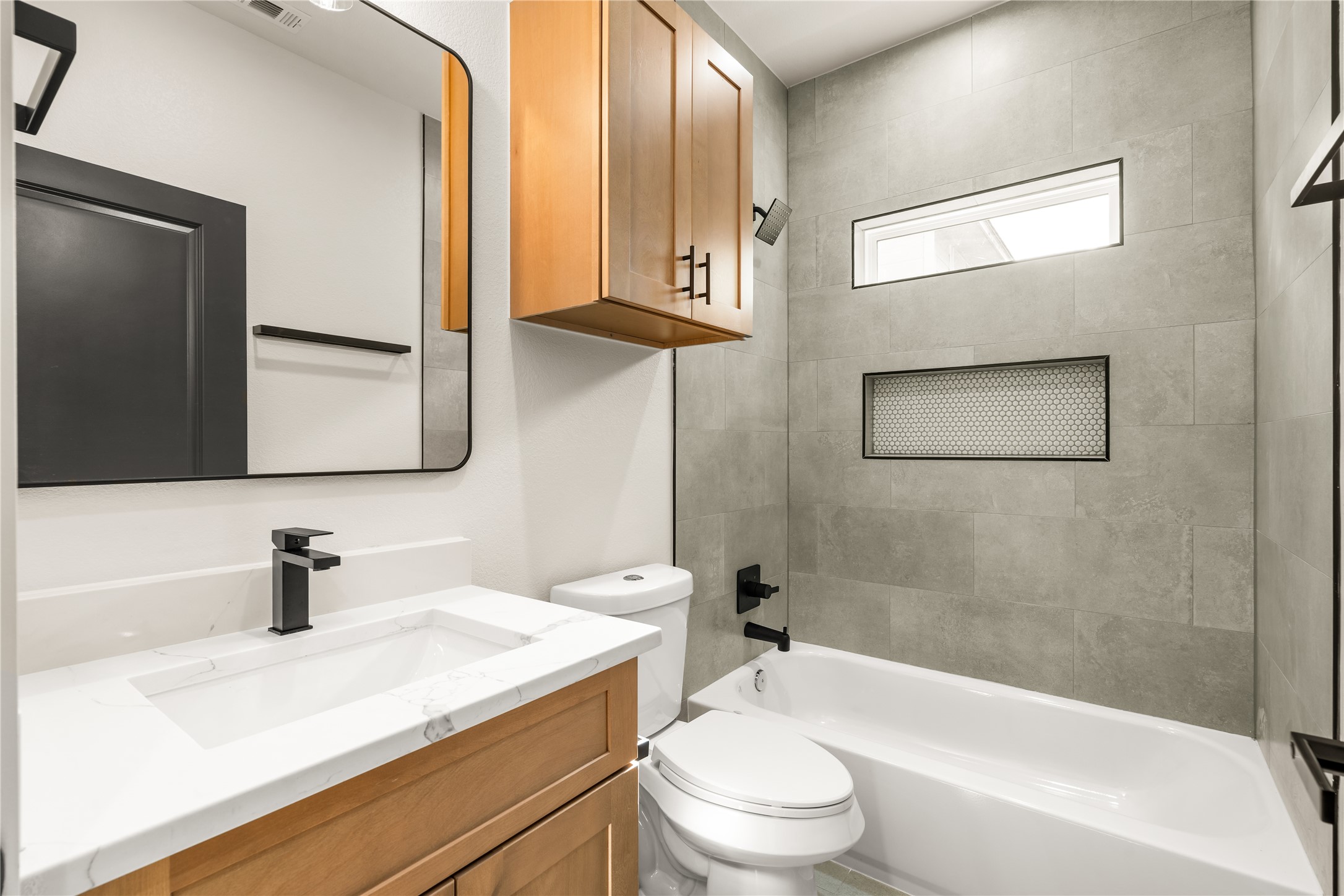 5321 Rue Street Houston, TX 77033 - Photo 18 of 23 Full secondary bathroom — designer tile surround extending to the ceiling, tub/shower combo with mosaic niche, and custom wood vanity.