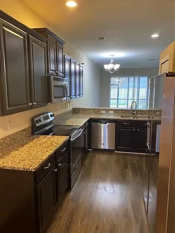 a kitchen with stainless steel appliances granite countertop a stove a sink and a microwave