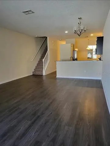 a view of a big room with wooden floor and a kitchen