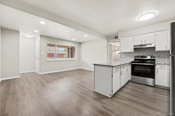 a kitchen with granite countertop a stove a sink and a refrigerator