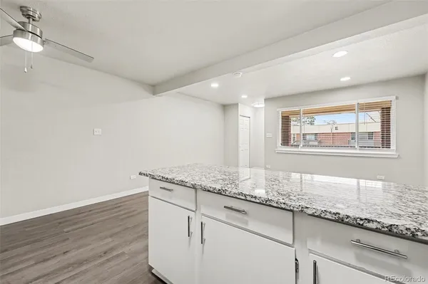 a hallway with granite countertop white cabinets and window