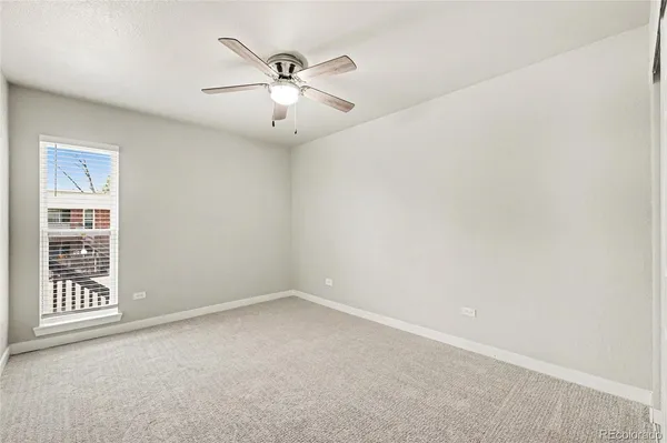 an empty room with windows and fan