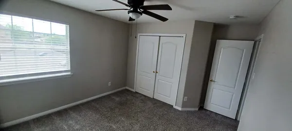 an empty room with windows and fan