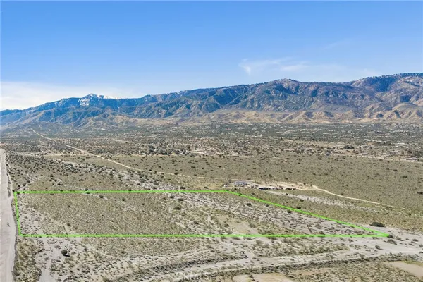 a view of a dry field with mountains in the background