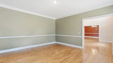 an empty room with wooden floor chandelier and windows