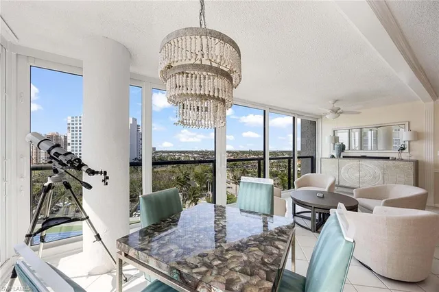 a living room with furniture a chandelier and a floor to ceiling window