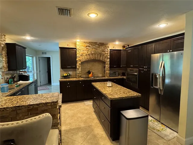 a kitchen with stainless steel appliances granite countertop a refrigerator a sink and a stove