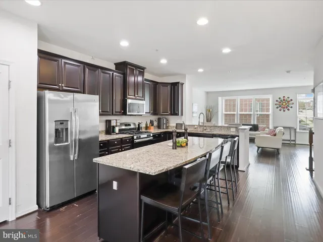 a kitchen with stainless steel appliances granite countertop a refrigerator a stove a sink a dining table and chairs