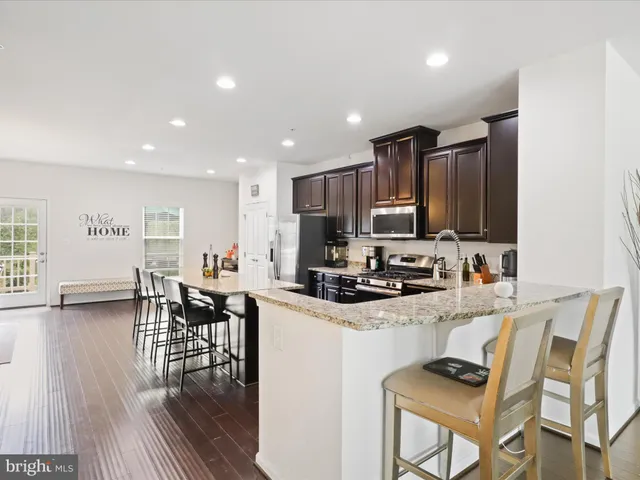 a kitchen with granite countertop a stove a sink a dining table and chairs