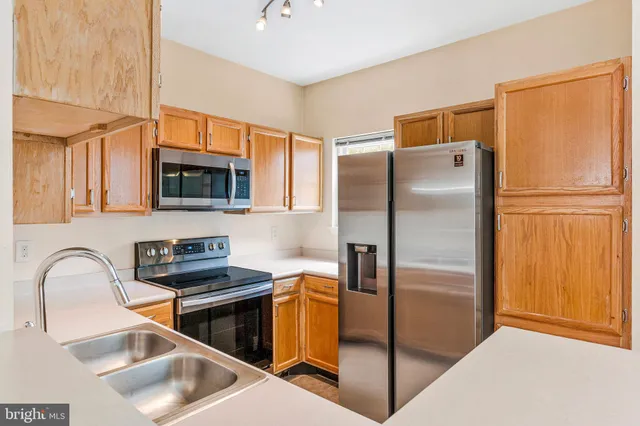 a kitchen with stainless steel appliances granite countertop a refrigerator a stove and a sink with wooden floor