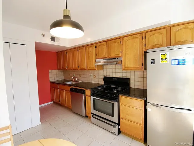 a kitchen with stainless steel appliances granite countertop a refrigerator a stove and a sink