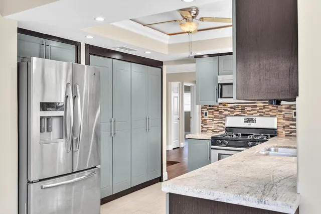 a kitchen with stainless steel appliances granite countertop a refrigerator a stove and a sink