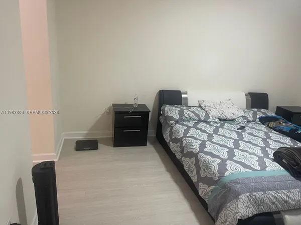 a bedroom with a bed and a lamp on dresser