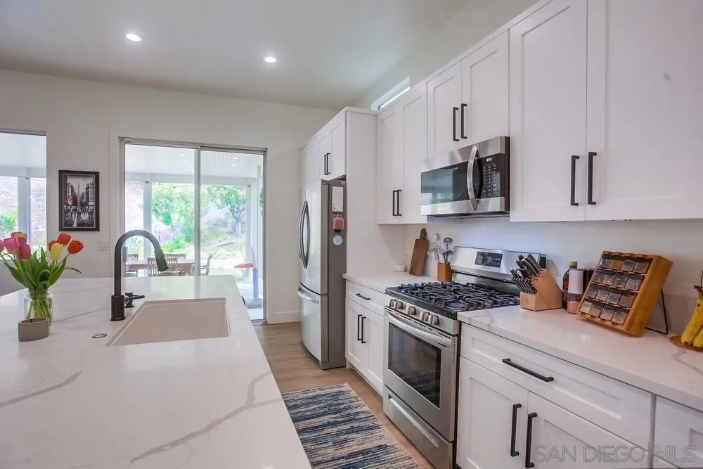 2322 Byron Place Carlsbad, CA 92008 - Photo 15 of 56 a kitchen with stainless steel appliances kitchen island granite countertop a stove a sink dishwasher and a refrigerator with wooden floor