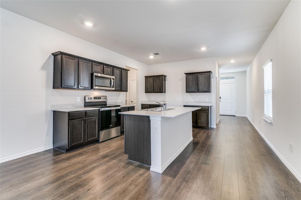 3025 Frazier Street Forney, TX 75126 - Photo 9 of 25 a kitchen with stainless steel appliances kitchen island wooden cabinets and granite counter tops