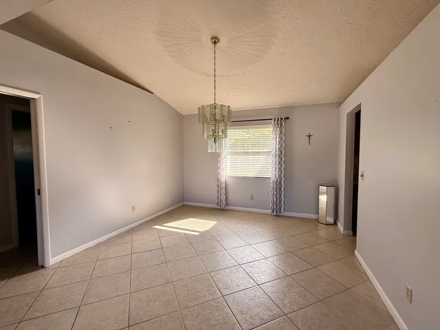 a view of an empty room with window and chandelier fan