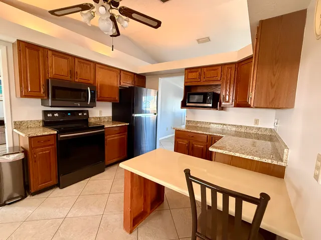 a kitchen with stainless steel appliances granite countertop a stove top oven a sink dishwasher a dining table and chairs with wooden floor