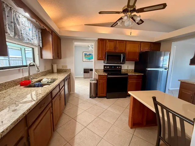 a kitchen with stainless steel appliances granite countertop a sink dishwasher stove a refrigerator a microwave oven with island and chairs