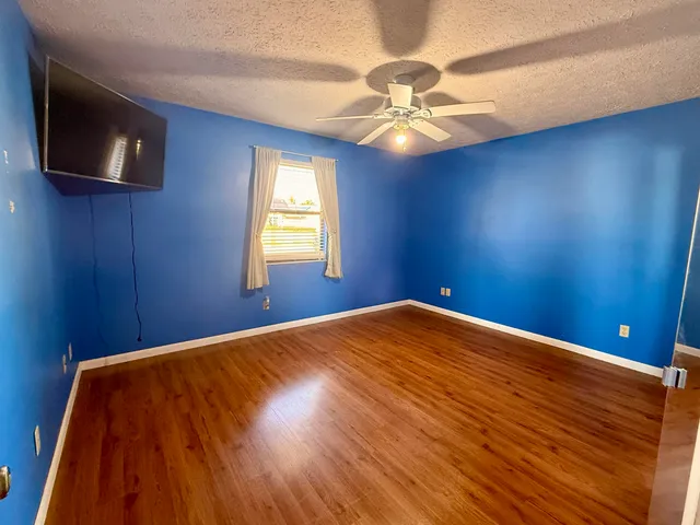 a view of a big room with wooden floor and chandelier fan