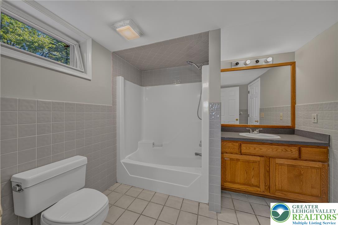 630 Clearfield Road Nazareth, PA 18064 - Photo 81 of 100 Tiled flooring and a wooden vanity define this functional bathroom space.