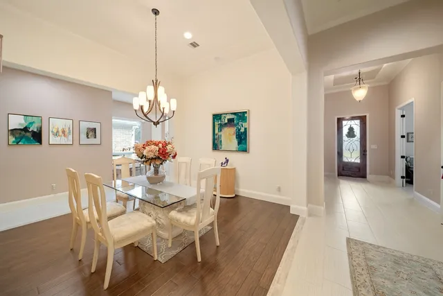 a dining room with wooden floor a chandelier a wooden table and chairs