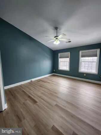 a view of empty room with wooden floor and fan