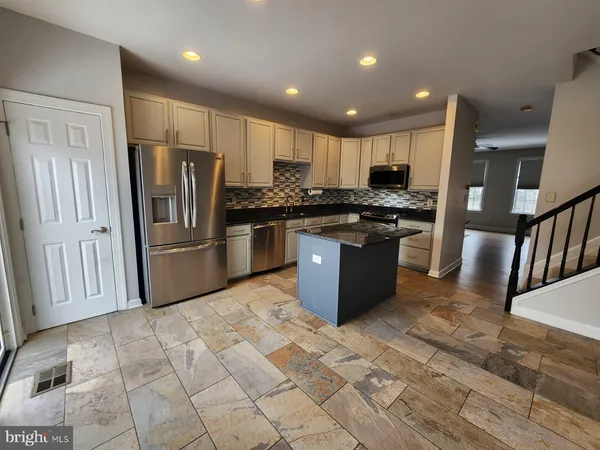 a kitchen with stainless steel appliances granite countertop a stove top oven a sink and a refrigerator