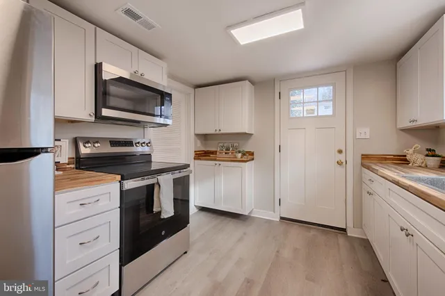 a kitchen with stainless steel appliances white cabinets a stove a sink and a microwave