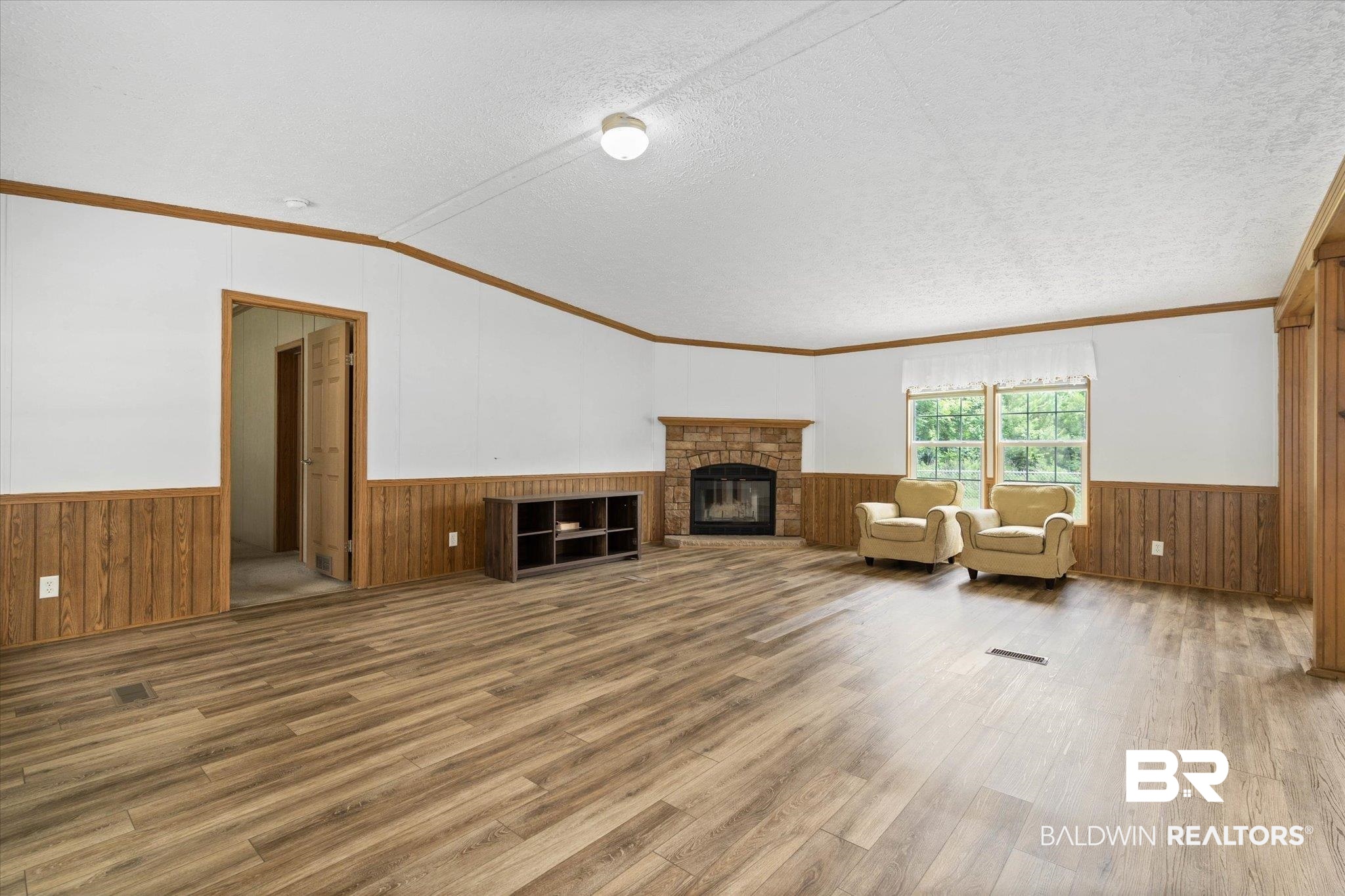 9335 Nathan Jordan Road Millry, AL 36558 - Photo 2 of 20 Unfurnished living room with wainscoting, wood finished floors, a textured ceiling, wooden walls, and ornamental molding