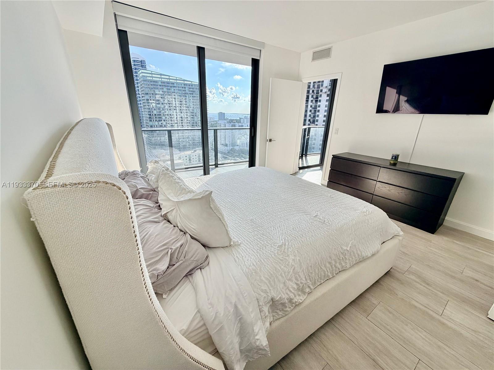 45 Southwest 9th Street, Unit 2606 Miami, FL 33130 - Photo 13 of 20 a bedroom with a bed and a large window