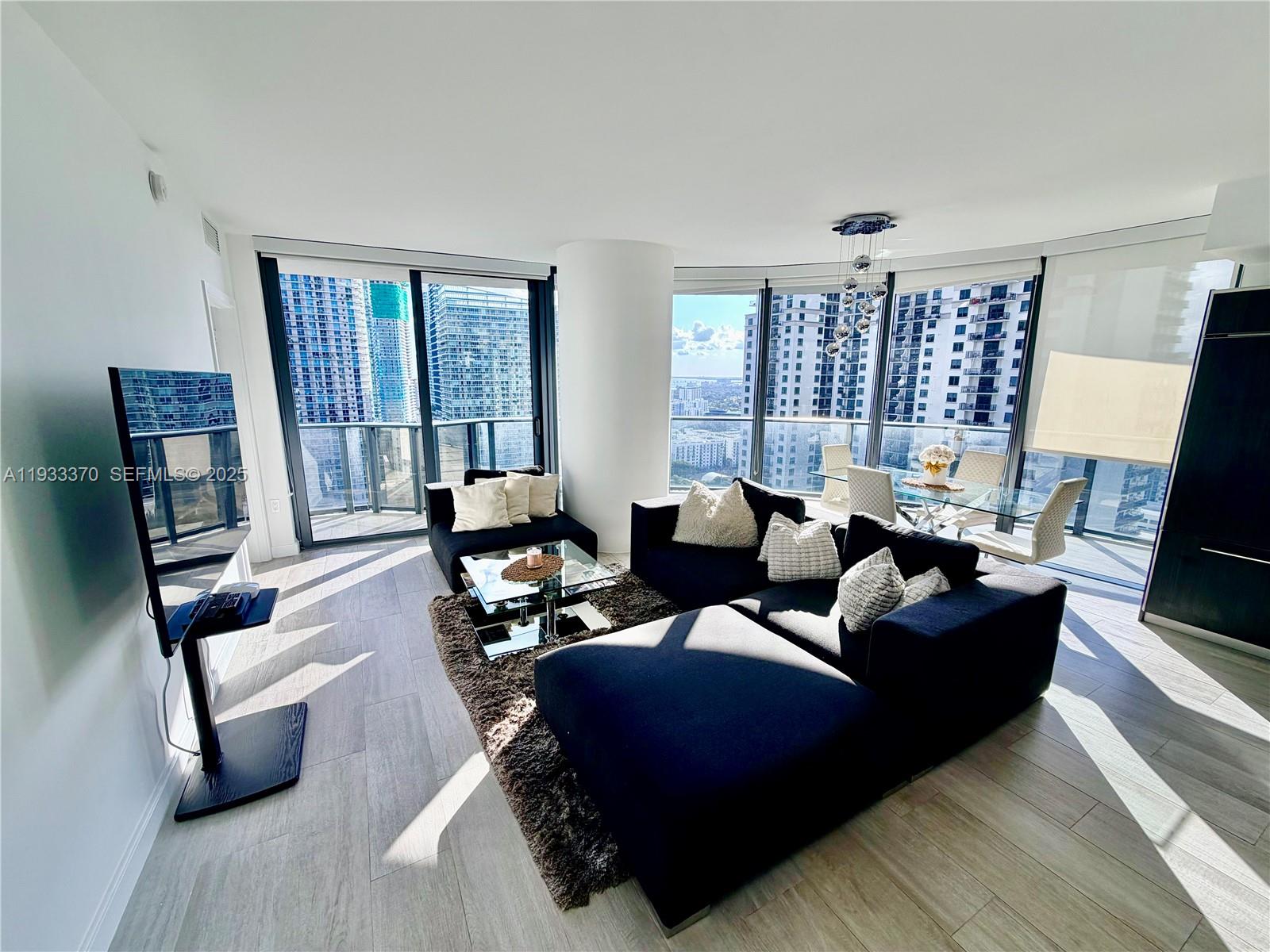 45 Southwest 9th Street, Unit 2606 Miami, FL 33130 - Photo 5 of 20 a living room with furniture and a flat screen tv