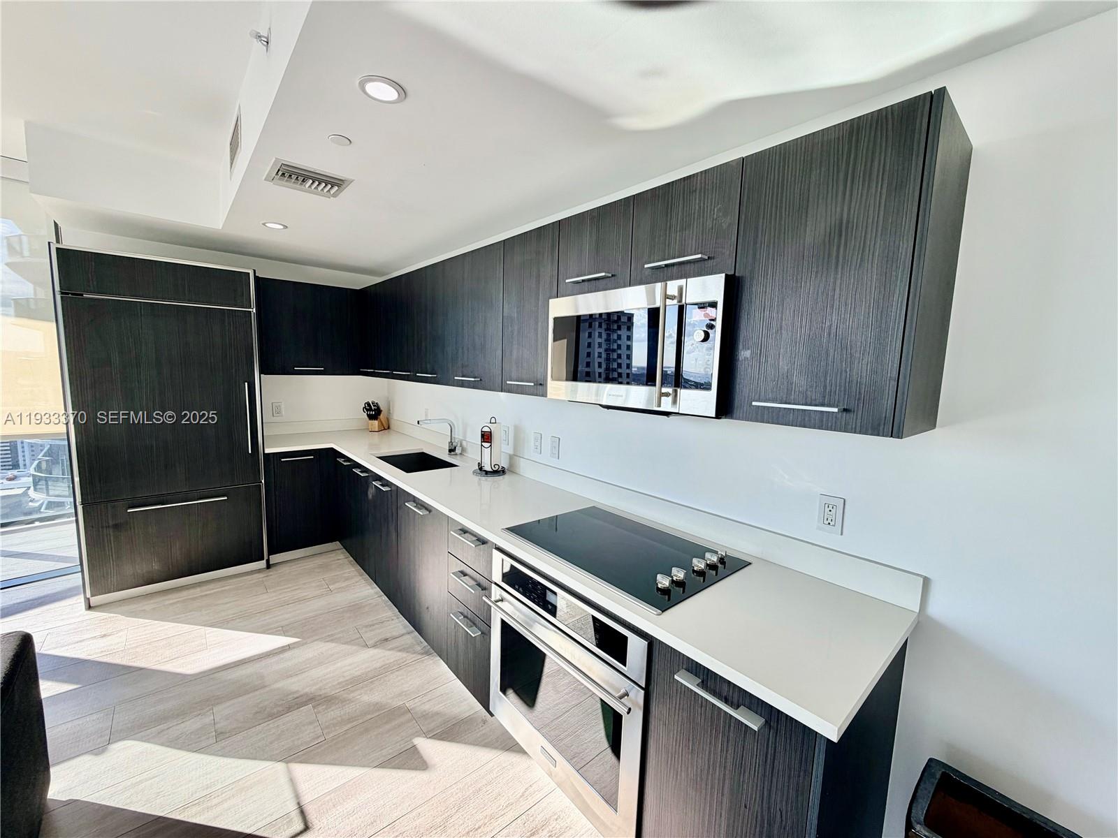 45 Southwest 9th Street, Unit 2606 Miami, FL 33130 - Photo 6 of 20 a large white kitchen with a stove a refrigerator and a sink