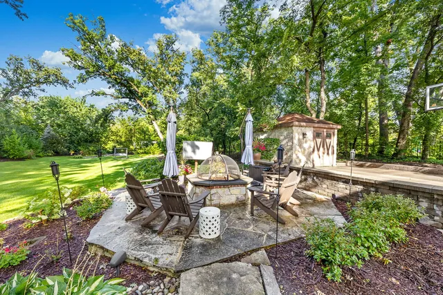 a view of a patio with table and chairs potted plants and large tree
