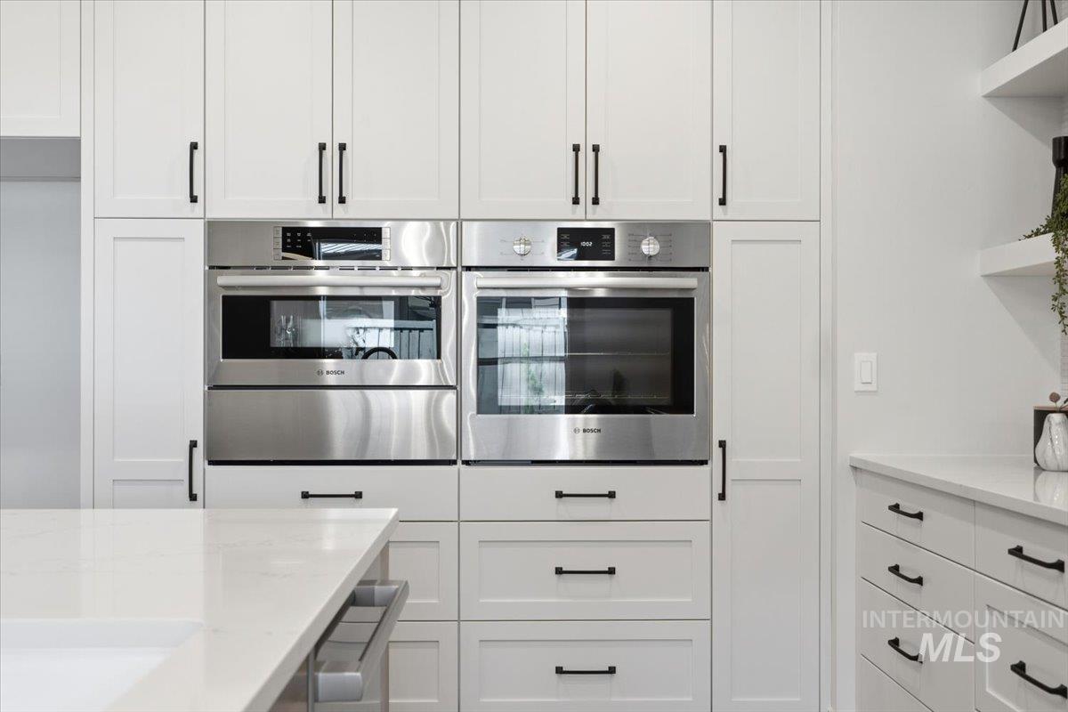 6762 South Messner Way Meridian, ID 83642 - Photo 7 of 35 Kitchen featuring white shaker-style cabinetry with black hardware, integrated double ovens, and white countertops