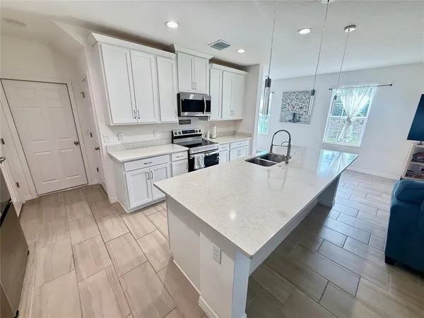 a kitchen with kitchen island white cabinets appliances and sink