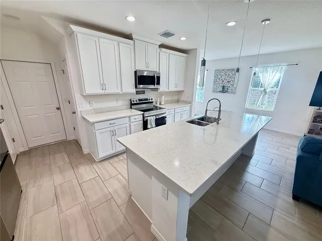 a kitchen with kitchen island white cabinets appliances and sink