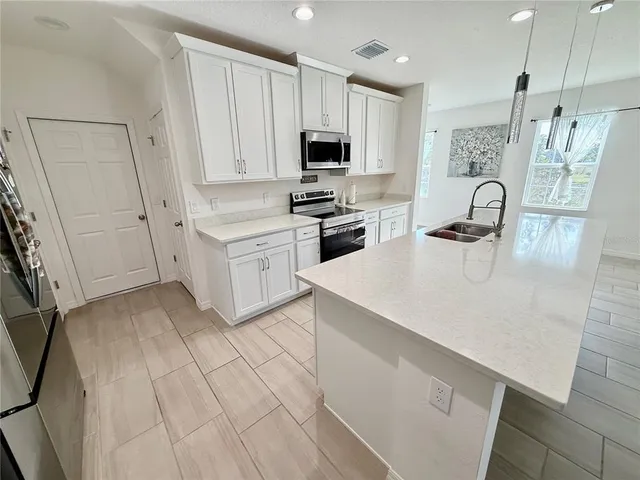 a large white kitchen with a sink a stove a microwave a refrigerator and a stove