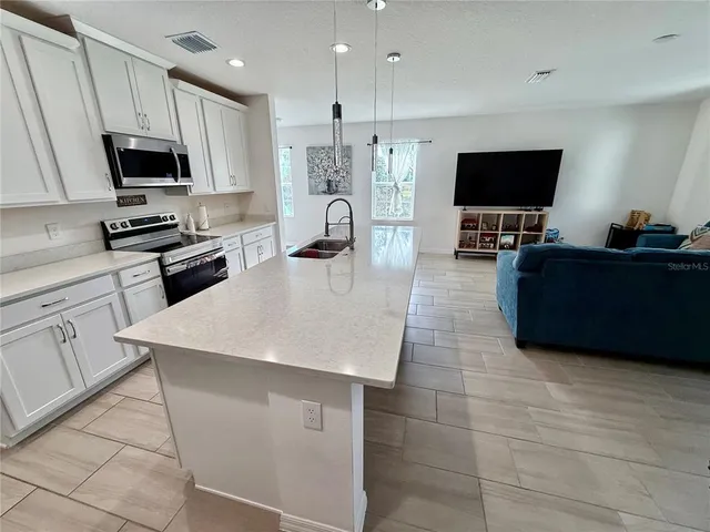 a kitchen with stainless steel appliances a stove a sink a microwave a refrigerator a stove a microwave and cabinets