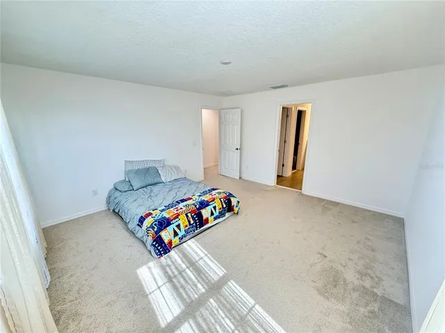 a spacious bedroom with a bed and a window