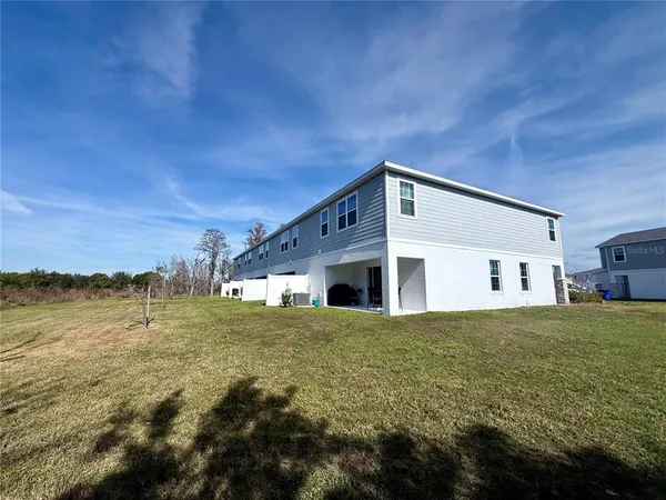 a large yard with lots of green space and house in the back