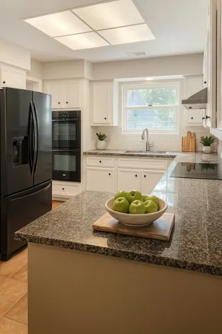 a large kitchen with granite countertop a stove a sink and a refrigerator