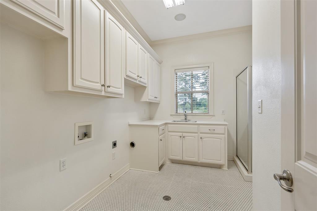 20389 County Road 178 Flint, TX 75762 - Photo 29 of 40 Utility room featuring extensive white cabinetry, a corner sink with a countertop, a glass-enclosed shower, a window with blinds, and white hexagonal tile flooring