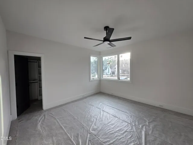 a view of a big room with a ceiling fan and windows