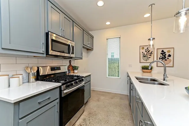 a kitchen with stainless steel appliances a sink a stove a microwave a center island and cabinets