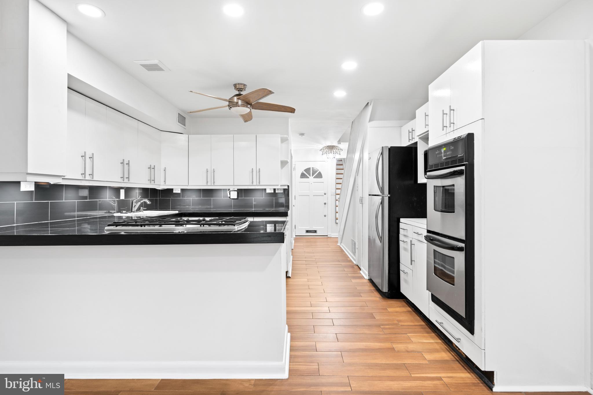 73 G Street Southwest, Unit 103 Washington, DC 20024 - Photo 6 of 35 a kitchen with stainless steel appliances granite countertop a refrigerator a stove and a sink with wooden floor