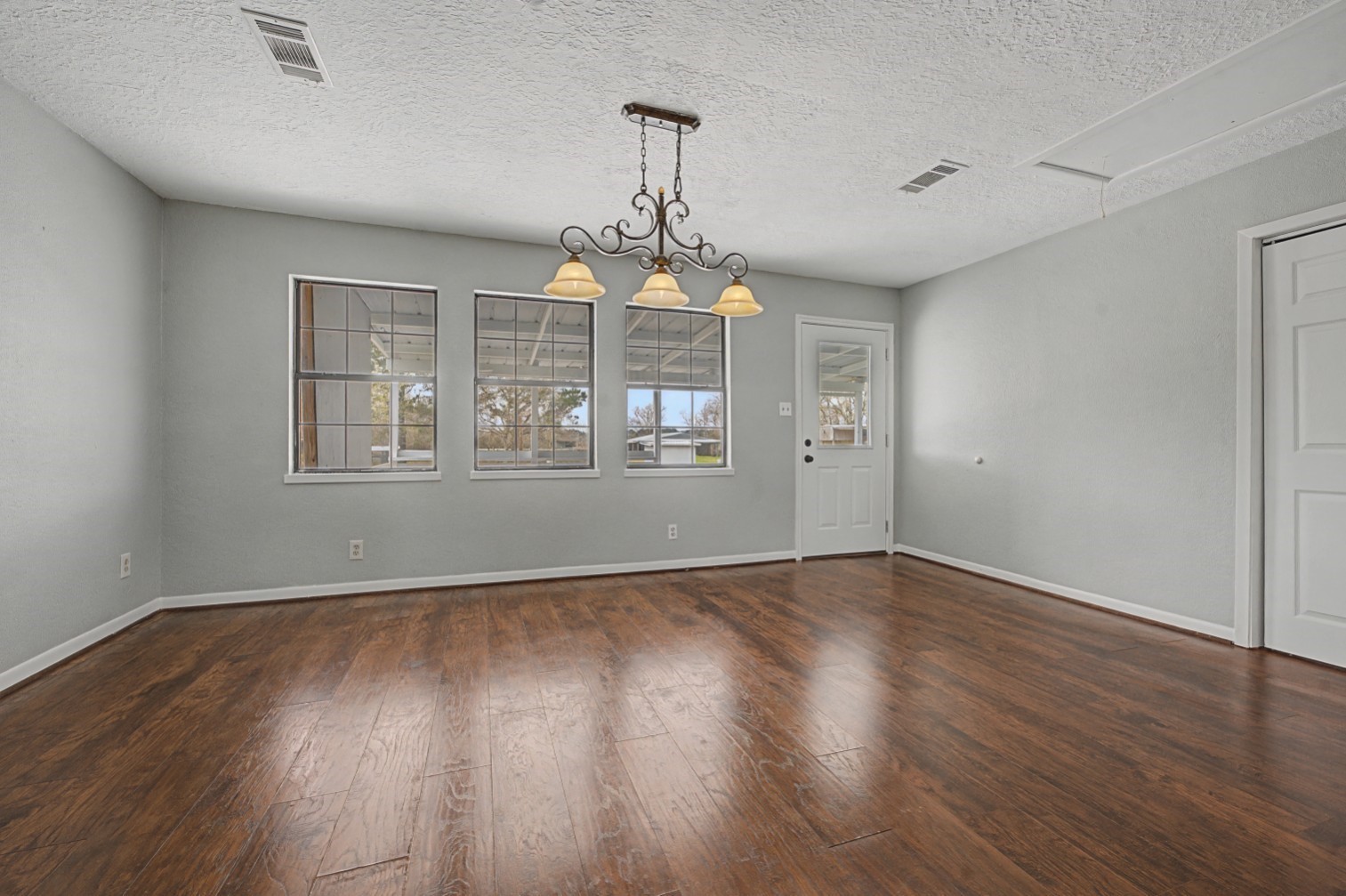 14077 Hamshire Road Hamshire, TX 77622 - Photo 11 of 39 Bright, spacious room, a classic chandelier, and large windows for natural light. Neutral wall colors create a versatile space for living or dining.
