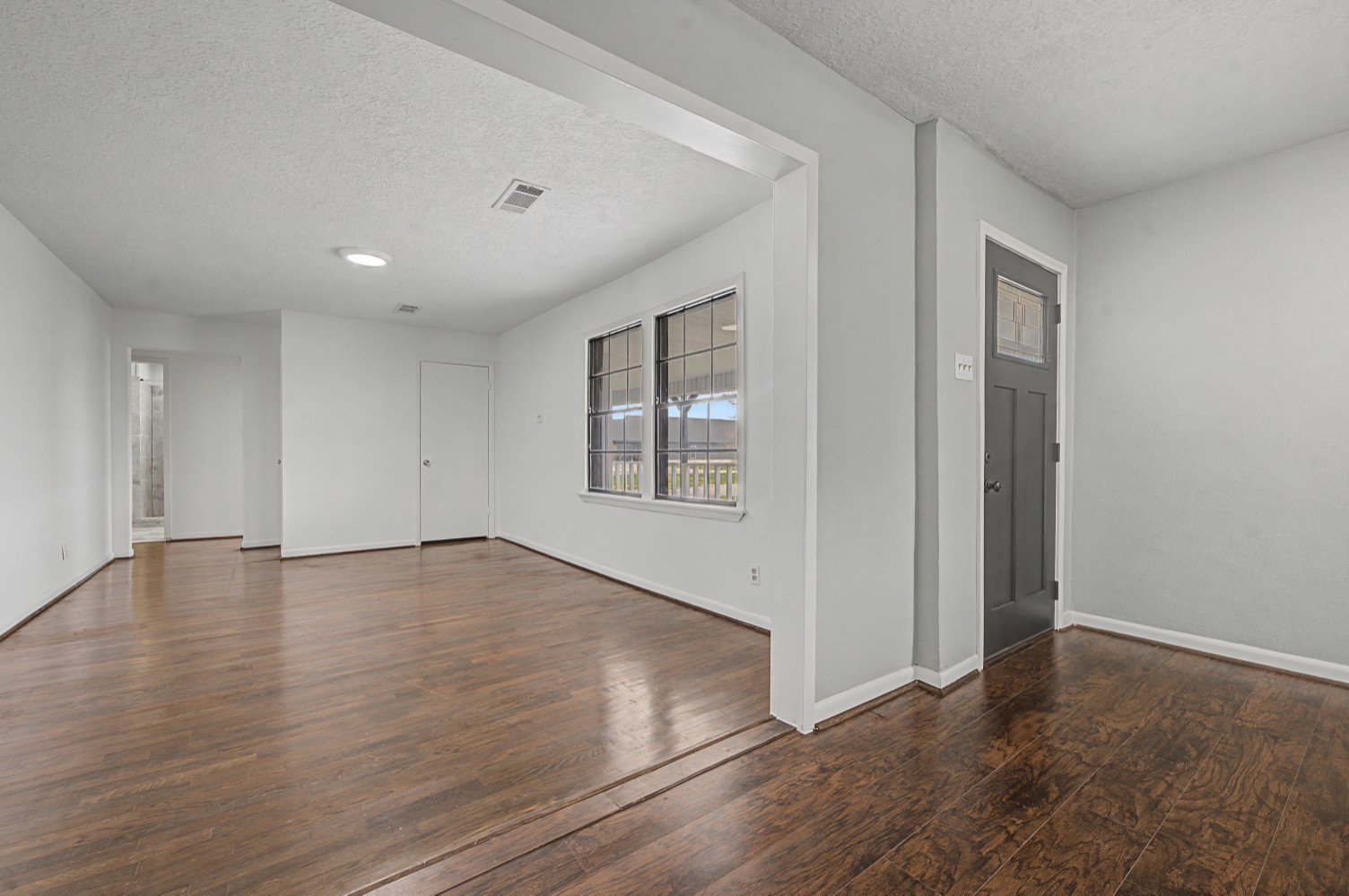 14077 Hamshire Road Hamshire, TX 77622 - Photo 15 of 39 This room features an open layout with beautiful floors and neutral walls, offering plenty of natural light from the large windows. It connects to a hallway and has a modern front door, creating a welcoming entrance.