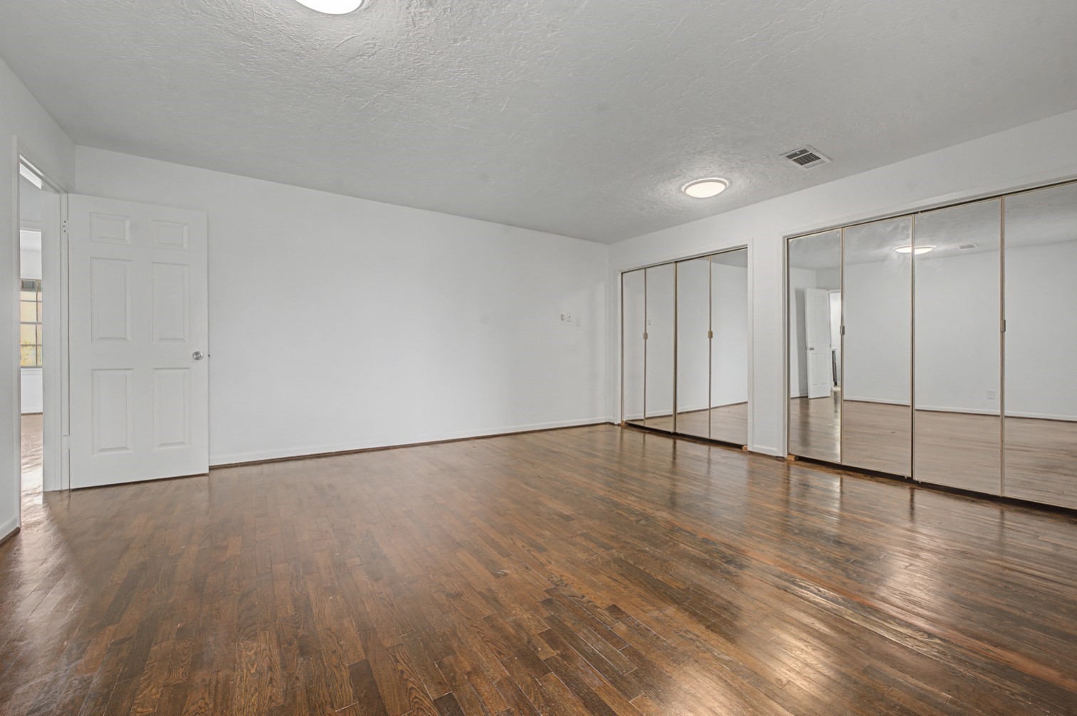 14077 Hamshire Road Hamshire, TX 77622 - Photo 18 of 39 Spacious primary room with lovely floors, neutral walls, and ample natural light. Features large mirrored closets, providing a sense of openness.