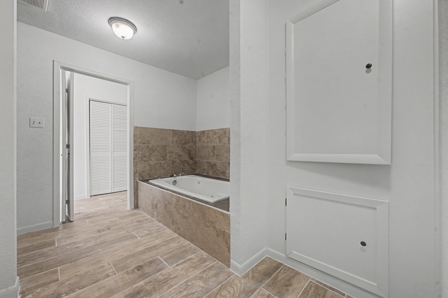 14077 Hamshire Road Hamshire, TX 77622 - Photo 23 of 39 This photo features a modern bathroom with a spacious jacuzzi bathtub surrounded by stone tile. The room has a white color scheme, creating a bright and inviting space.
